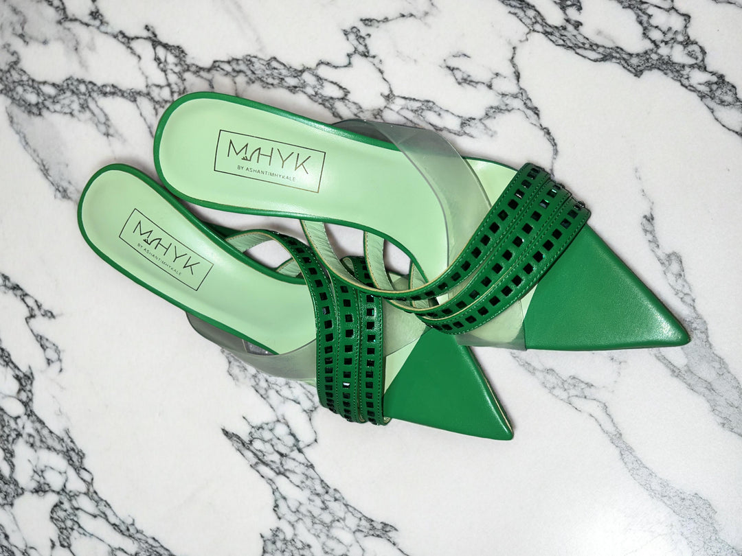 Envy green mules positioned diagonally to showcase side profile, open back, and vibrant green color on a neutral surface.