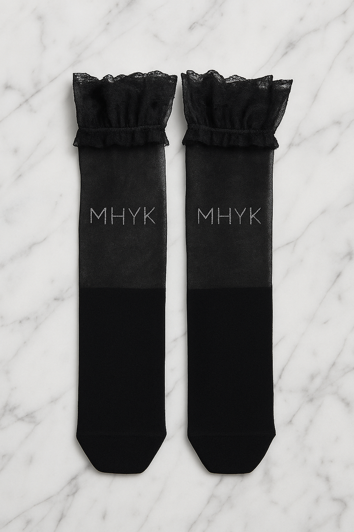 MHYK Original over-the-knee lace socks laid flat in aerial view on a white marble slab, showing intricate lace pattern and scalloped edges.