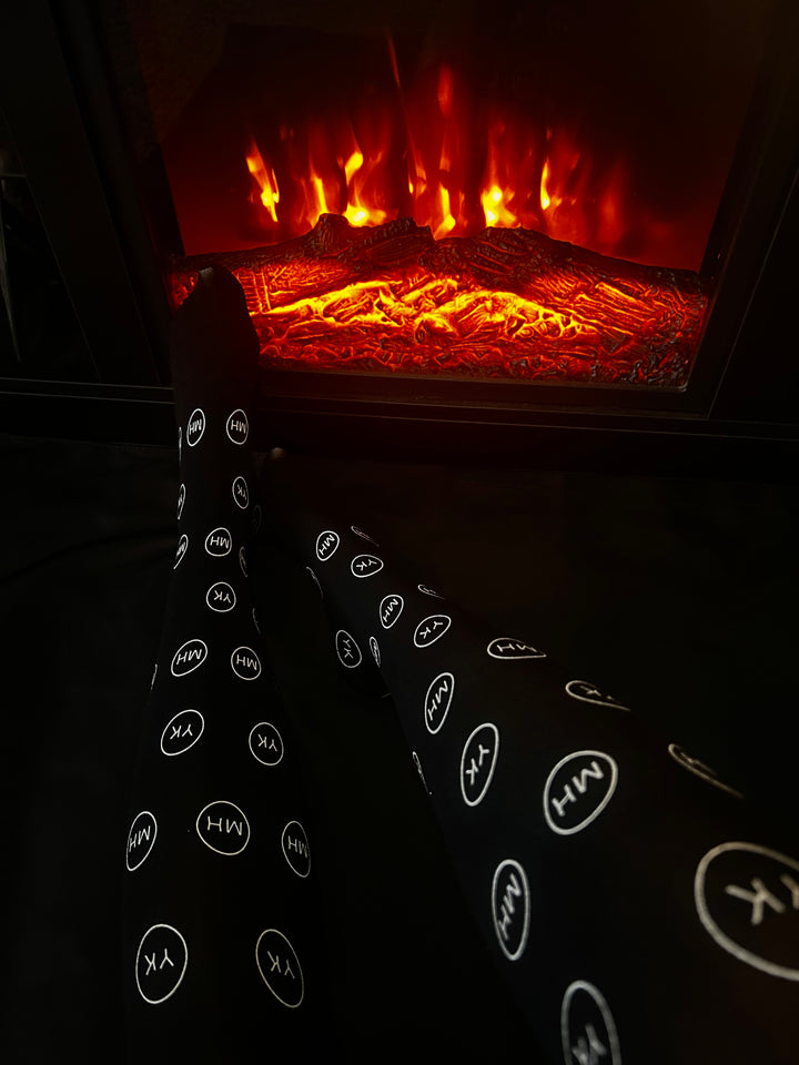 Model wearing black logo over the knee socks by the fire place 